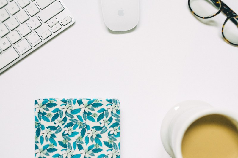 an overhead shot of a keyboard a mouse a pair of glasses a cup of coffee and a coaster on a white surface, coffee and glasses in flatlay 4k