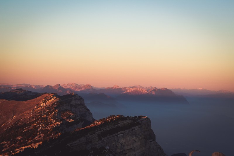jagged mountain ridges towering over a valley covered by a thick mist, amazing sunset 4k