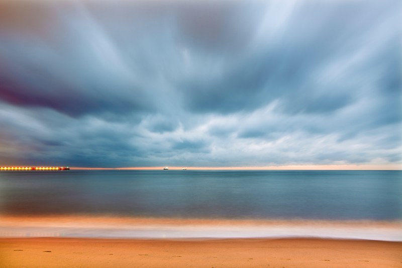 a scenic sunset with cloudy skies casting over playa de la misericordia in malaga, sunset over a beach in malaga 4k