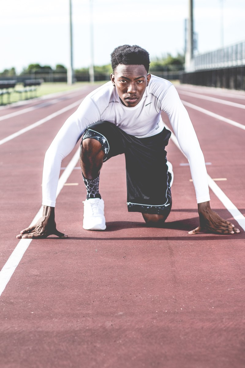 a man wearing a white long sleeve shirt shorts and sneakers getting ready for a run on a track, the runner 4k