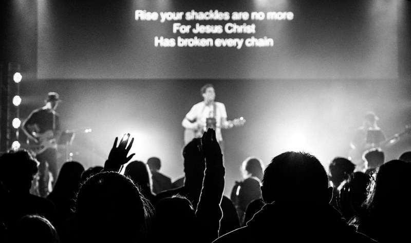 silhouettes of an audience holding their arms up during a christian rock concert, worship 4k