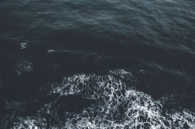 an overhead drone shot of foam and ripples in the dark blue ocean, ripples and waves in the deep blue 4k