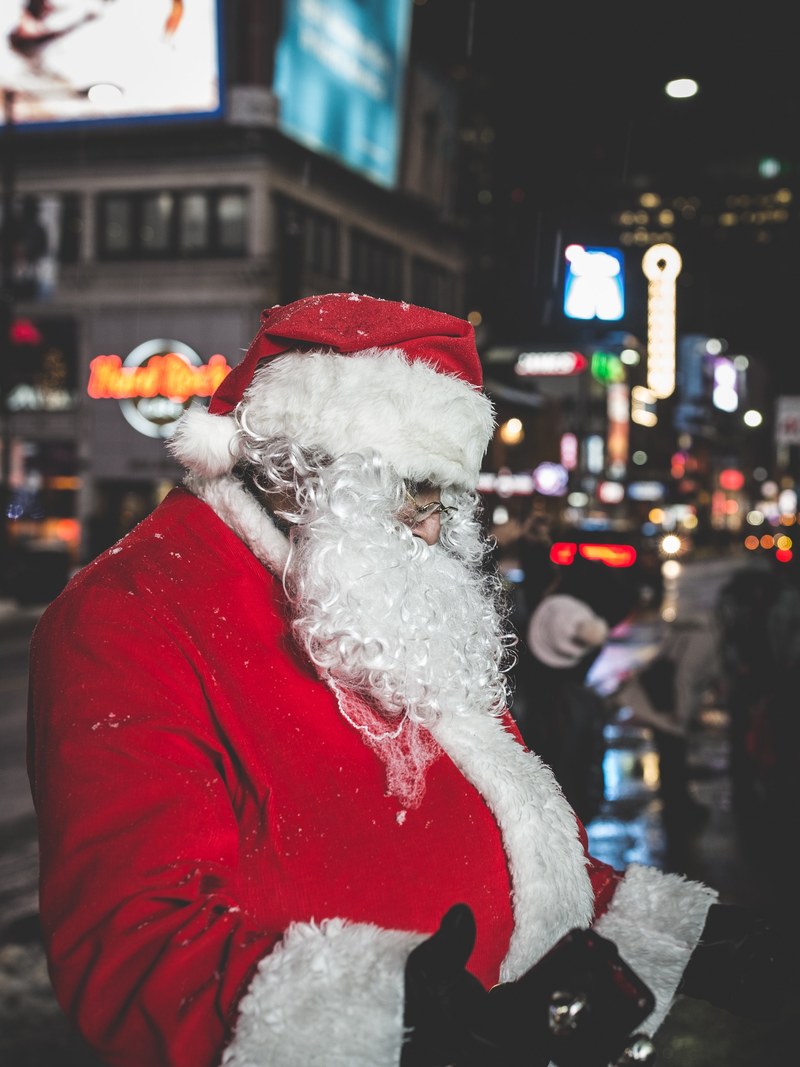 a man dressed as father christmas standing in the street at dundas square at night, santa 4k