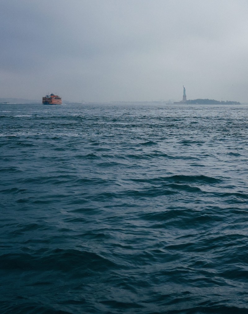 the statue of liberty and a cargo ship from the distance on a foggy day, the statue of liberty 4k
