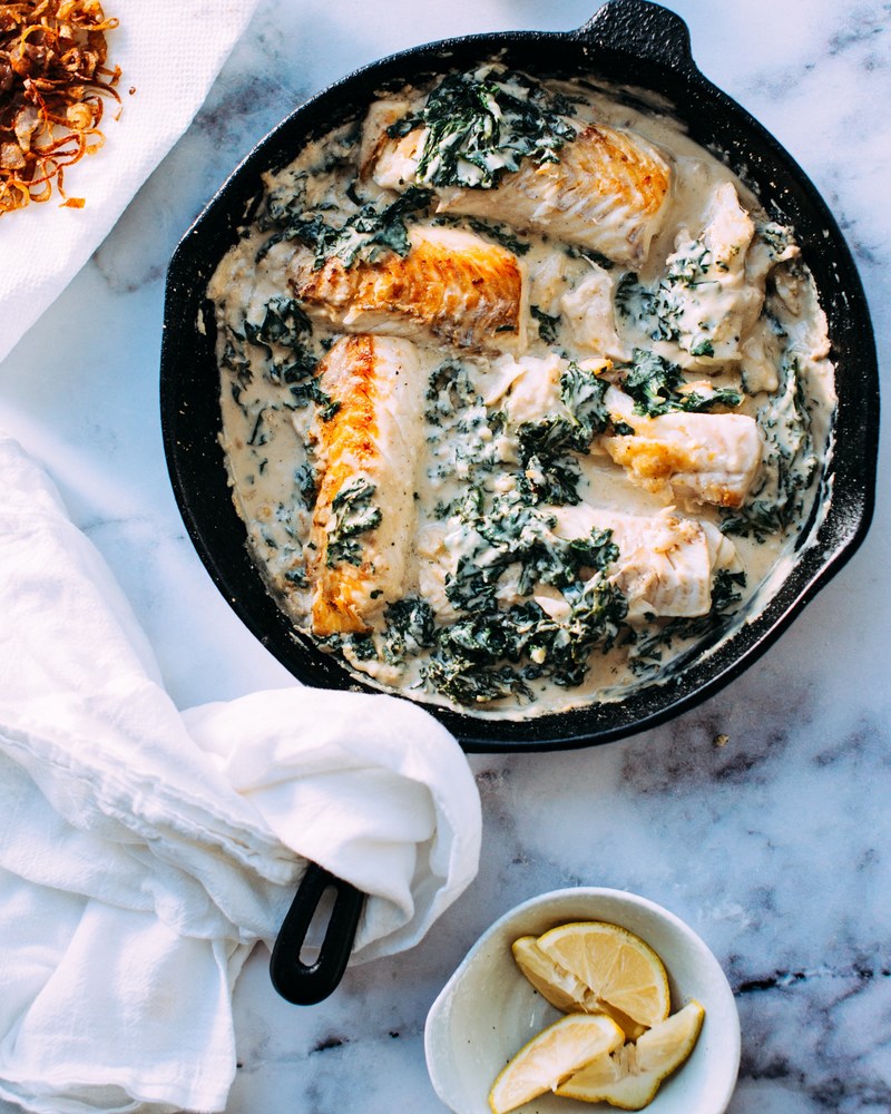 cast iron skillet with sauteed fish in a cream sauce with herbs, creamy fish dinner 4k
