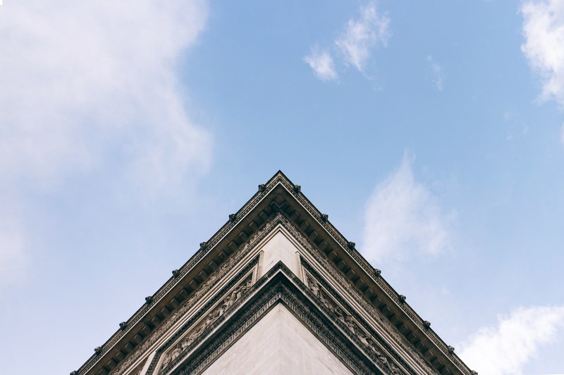 the corner of a stone building with a backdrop of blue skies and clouds, building corner with clouds 4k