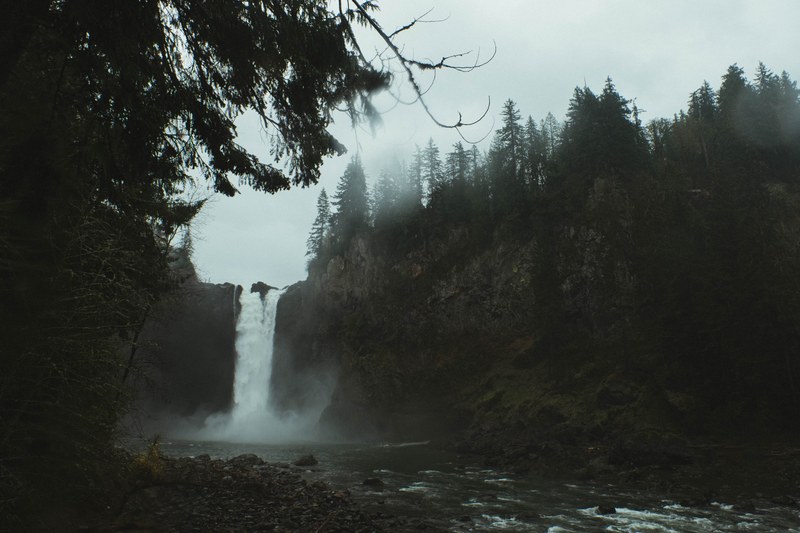a low waterfall pouring down into a forest stream, rainy day waterfall 4k