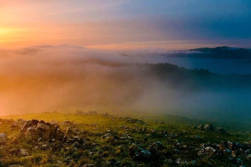 rainbow colored fog and smoke over rocky hillsides, rainbow clouds in marin county 4k