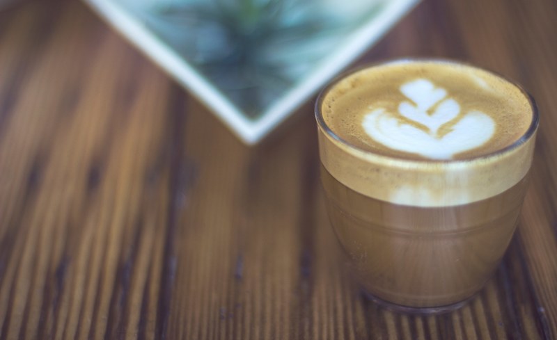 a cup of coffee with latte art in a glass on a wooden table in cincinnati, latte in glass in cincinnati 4k