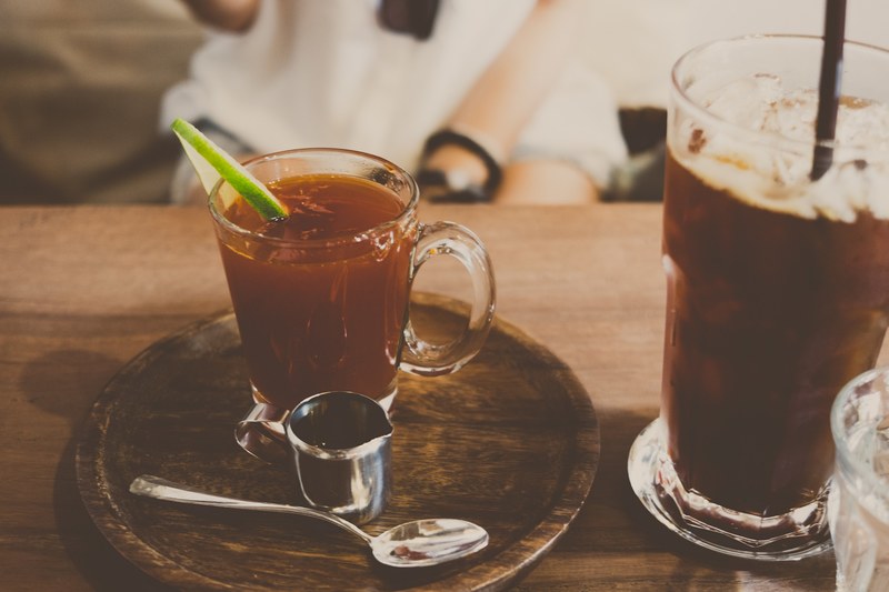 a cocktail in a glass mug on a plate with a silver dish and spoon next to a larger glass at yellow pumpkin, yellow pumpkin drinks 4k