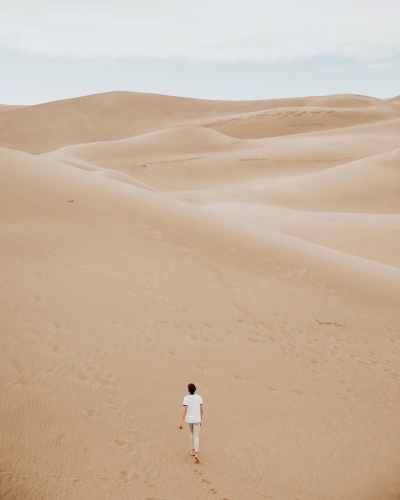 walking alone through the dunes lone tree desert, desolate desert hike 4k