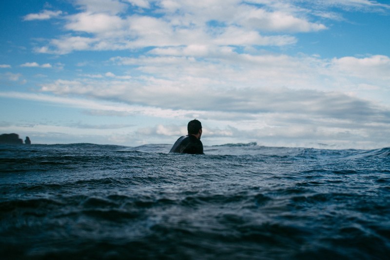 person floating in the ocean at piha beach, person floating in ocean 4k