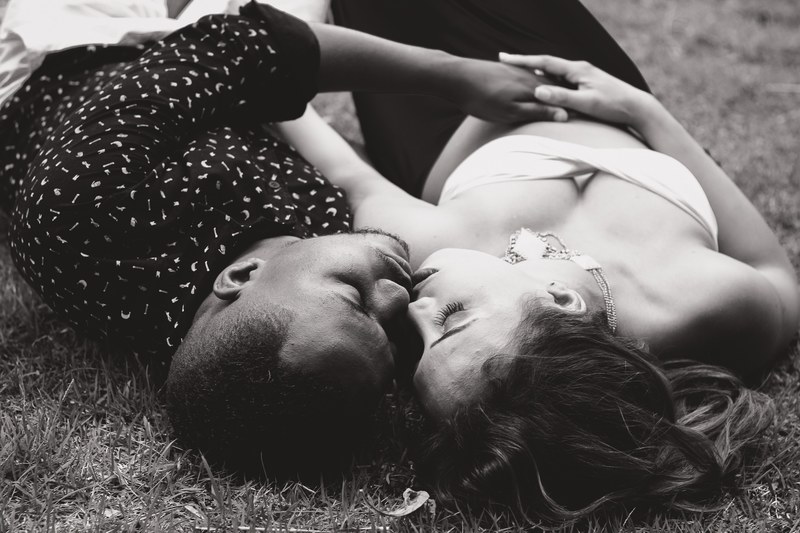 a man and a woman lying down on grass cuddle and kiss in black and white, couple kisses 4k