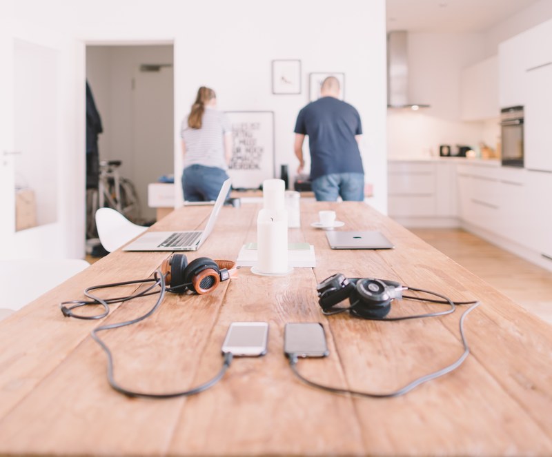 a man and a woman preparing food in a one room apartment with laptops on a long table, couple working at home 4k