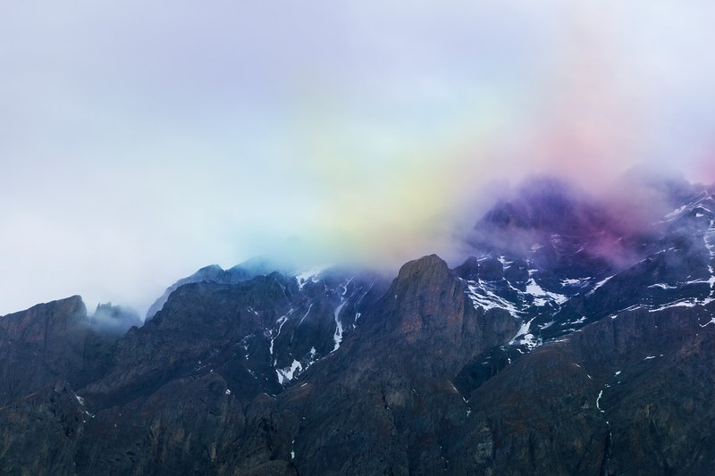 rainbow colored smoke and clouds over dark mountains in ovronnaz, rainbow mountains 4k