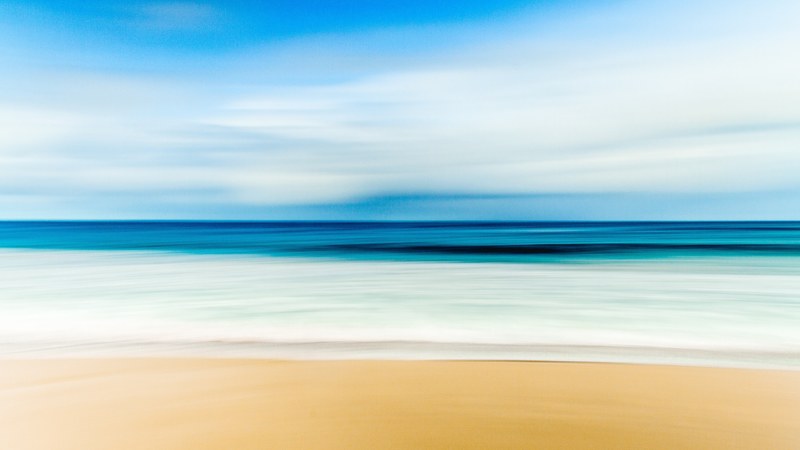 ocean washing on the sandy shore on a clear day at ulladulla, blur 4k