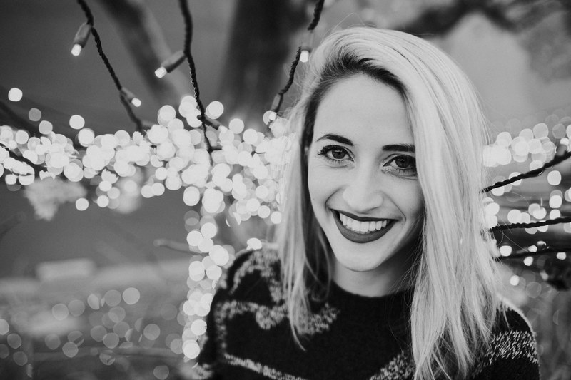 happy young woman smiles among strings of christmas lights, tree lights and woman smiling 4k