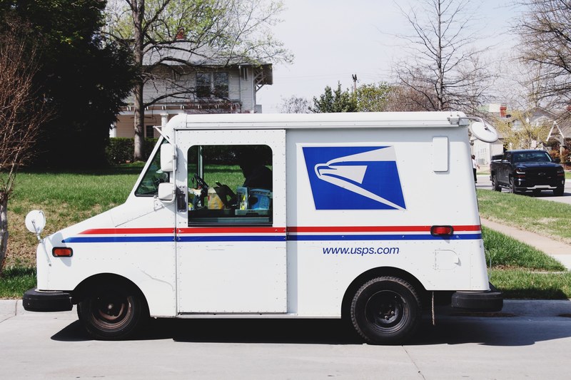 a mailman sitting in a mail truck sorting mail parked outside of a house in tulsa, mail time 4k