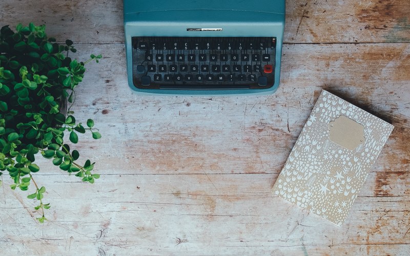 overhead shot of a turquoise typewriter next to a beige notebook and a plant, desk top 4k