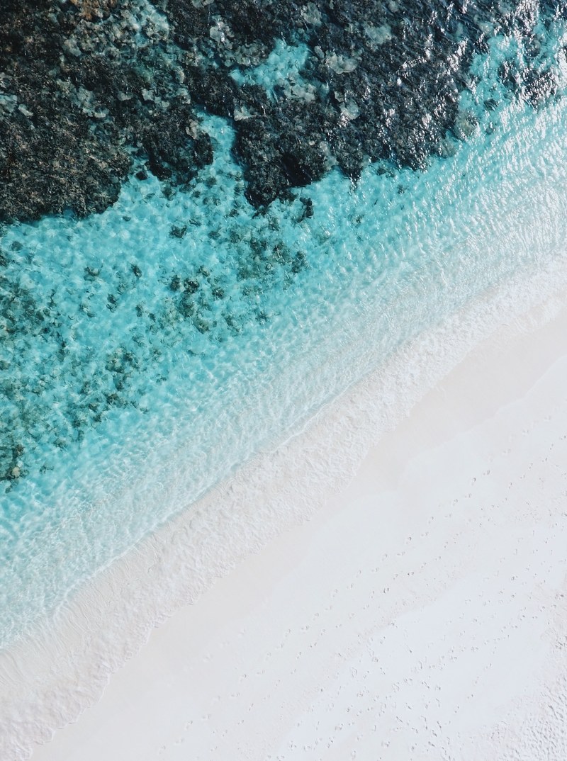 drone view of a white sandy beach by the clear ocean in bathalaa, layers_ 4k