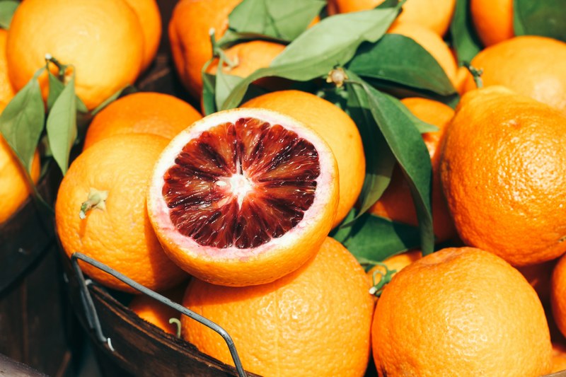 basket of blood oranges and leaves with one cut in half, basket of blood oranges 4k