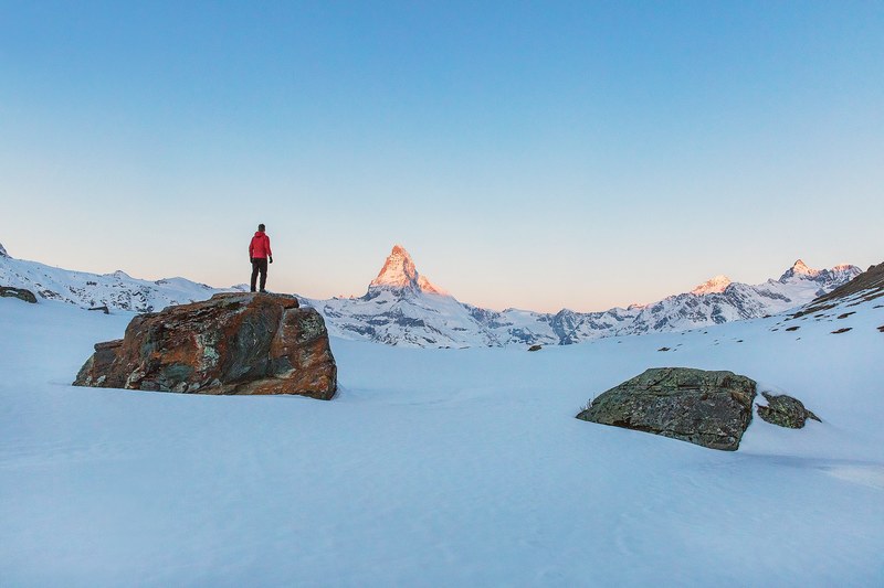a man standing on a tall rock at the alps in zermatt switzerland, switzerland winter alps 4k