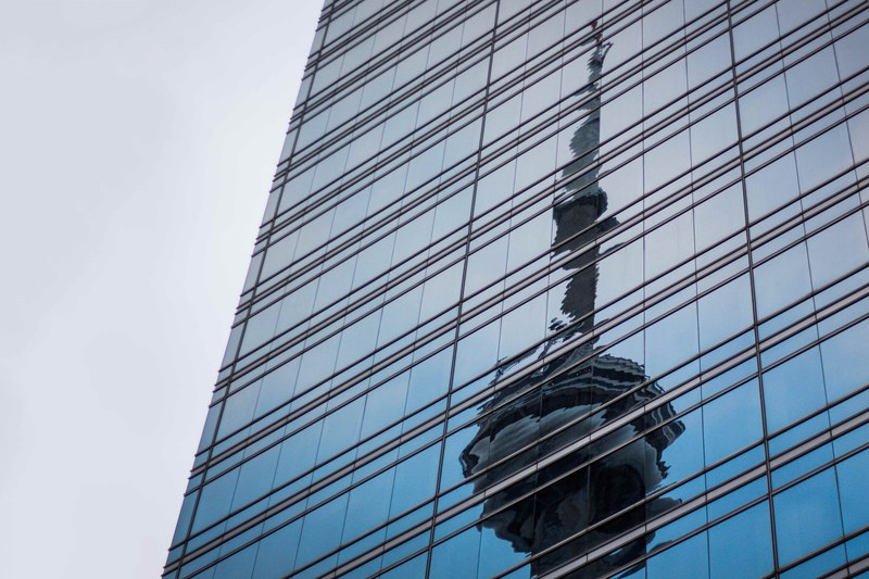 corporate skyscraper window during daytime with reflection of cn tower front west street, distorted reflection of cn tower 4k