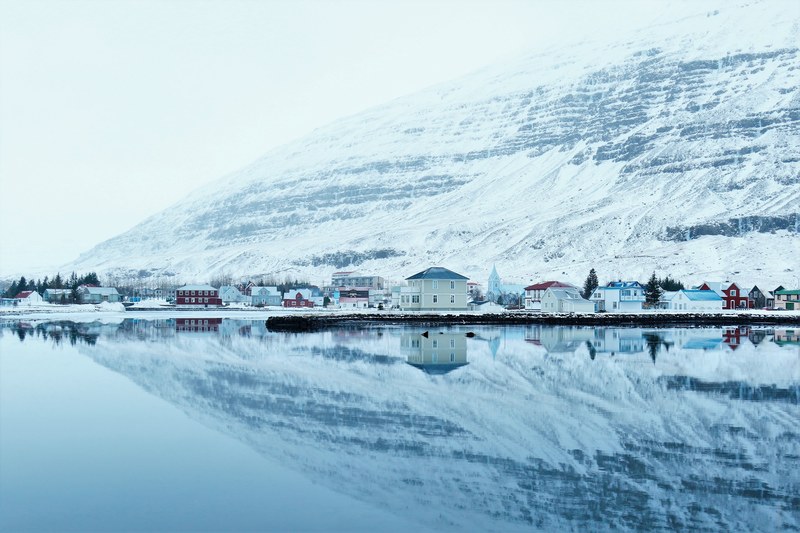 a snowy village reflection in the water with a mountain view, the reflection of a snowy mountain village 4k