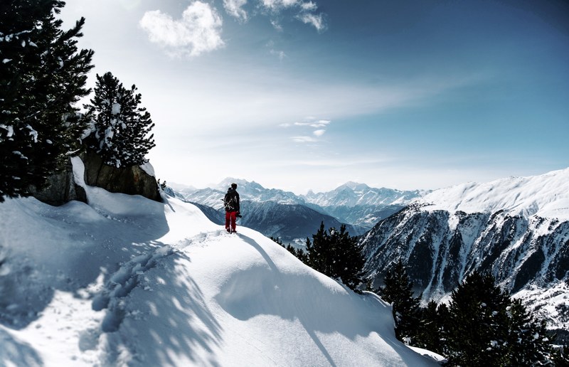 a hiker looks out onto snowy mountains, mountain hiker in snow 4k