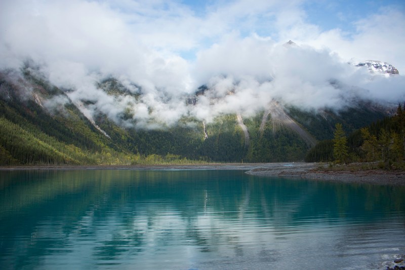 grassy mountainside of mount robson near calm waters on a cloudy day, mount robson in clouds 4k