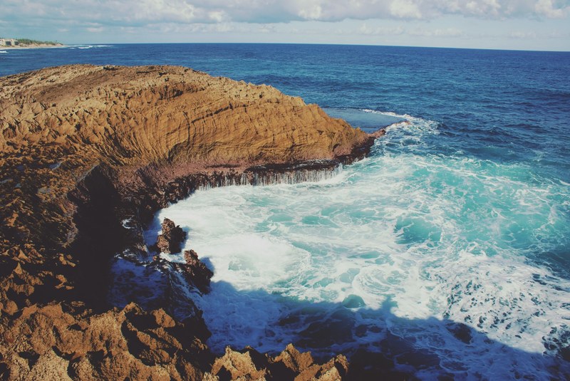 blue water and foaming white waves crashing against the rocky shoreline at puerto rico, waves against the rocks 4k