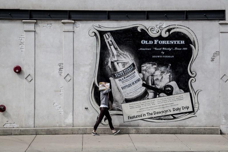 a person walking by an advertisement poster in front of a building in central chicago illinois usa, a person walking by a poster 4k