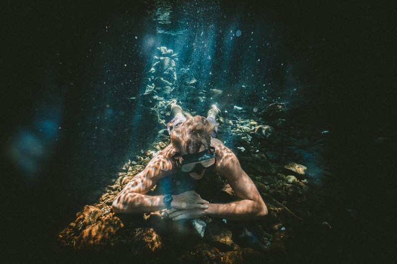 an underwater photo of a man snorkeling in a cave in the ocean, relax under the sea 4k