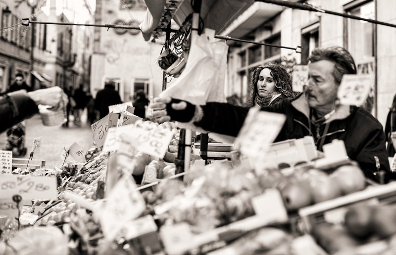 a black and white shot of people selecting produce at a market stall, the lady in the street 4k
