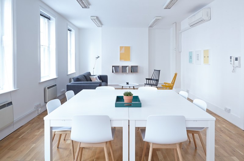 two white tables joined together in a clean white room with a sofa, stylish meeting room 4k