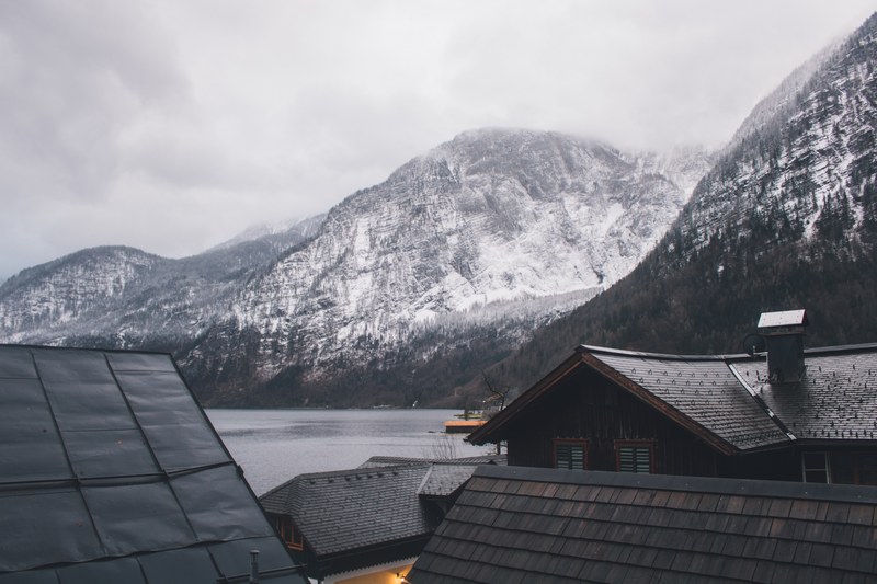 rooftop view of houses and snow covered mountains surrounding it with water in hallstatt, _rooftops mountain snow and lake 4k