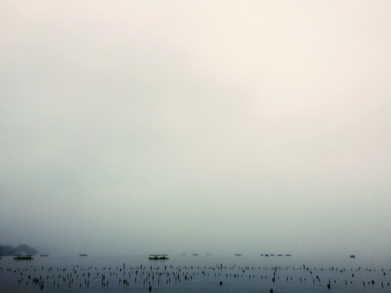 boats sit on serene waters on a foggy day in the west lake, wildness 4k