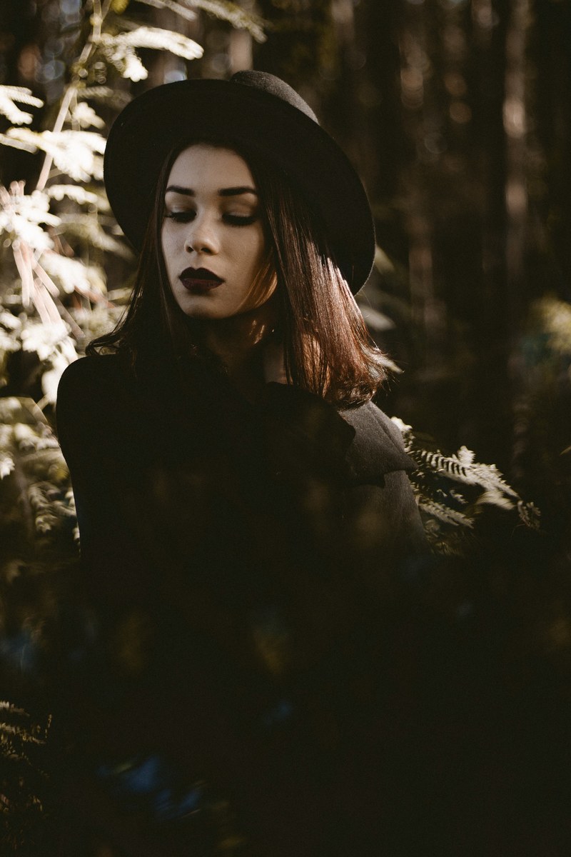 woman in all black with dark makeup posing outside, dark makeup look 4k