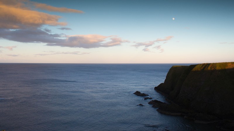 green cliff above the calm sea with clouds and the moon in the background, green cliff calm sea 4k