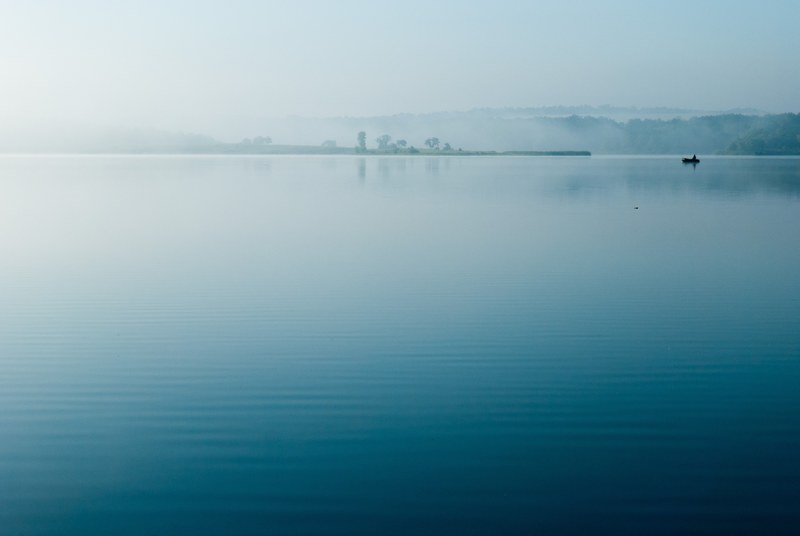 boats sit in calm blue waters on a misty evening, early morning lake 4k