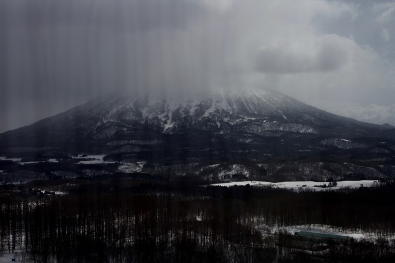 a massive mountain towering over wintry landscape as clouds gather around its peak, massive mountain in clouds 4k