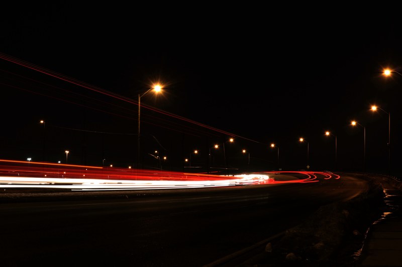 a dark street in ontario with head light trails and street lamps running down the road, long exposure 4k
