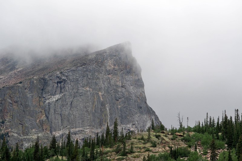 a steep rock face wreathed in fog, rock face in clouds 4k