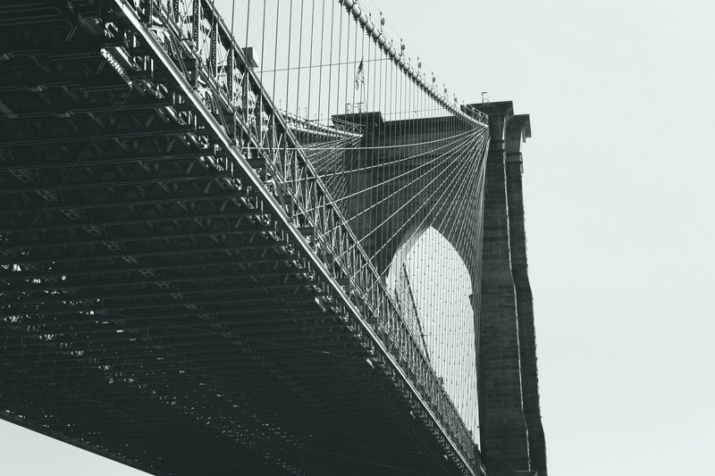 black and white shot of brooklyn bridge from below with clear sky, monochrome brooklyn bridge 4k