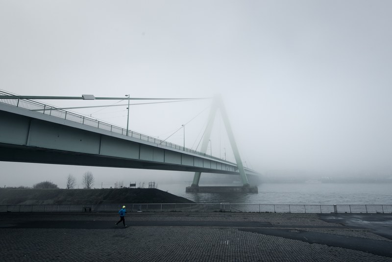 a view of a suspension bridge on a foggy misty day, fog over a bridge 4k