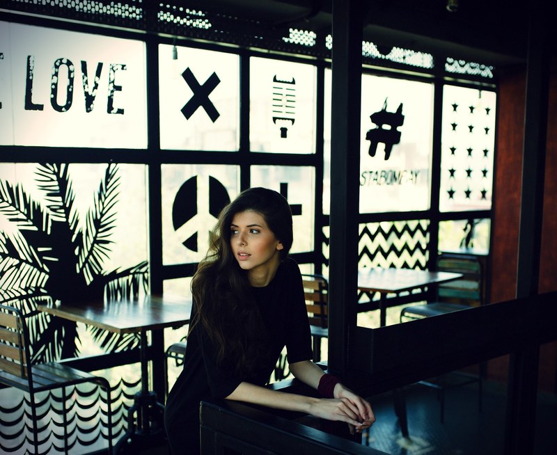 a young woman sits at a table in a cafe with decorated frosted windows, young woman at a counter 4k