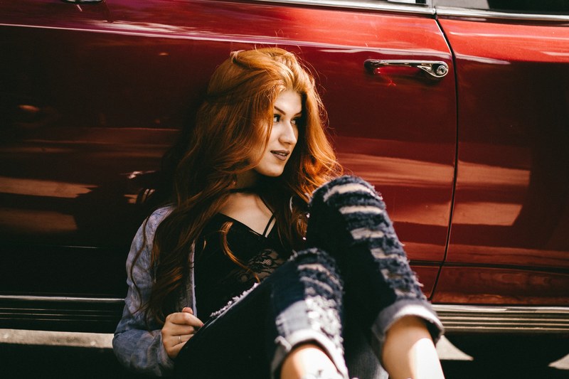 red haired woman sitting against a shiny red car, woman sitting against car 4k