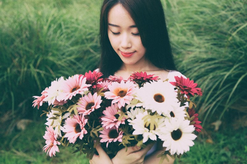 a dark haired woman holding a large bouquet of pink and white flowers in a meadow, woman with a bouquet in the meadow 4k
