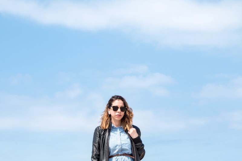 woman in black leather jacket and sunglasses posing in front of blue skies at santa monica state beach, woman posing in sunglasses 4k