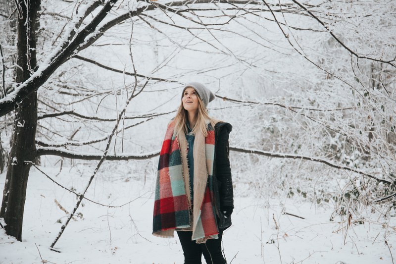 happy woman in a hat and scarf stares in awe at snowy trees, in a winter wonderland 4k
